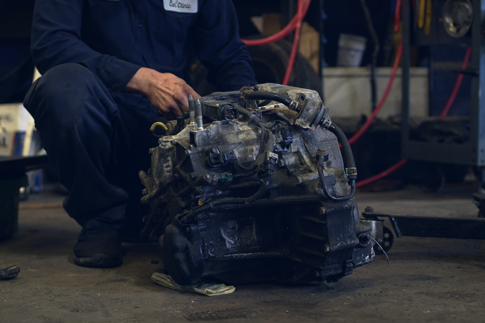A technician with a transmission pulled from a car